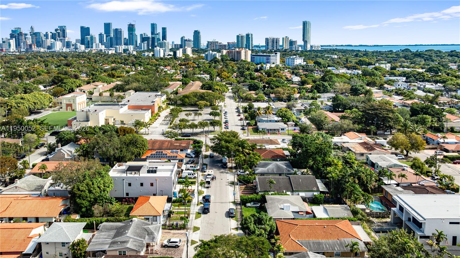 An aerial view shows a residential street with houses and trees leading toward a city skyline — 1428 SW 20th St, Miami FL 33145, MIAMI, FL