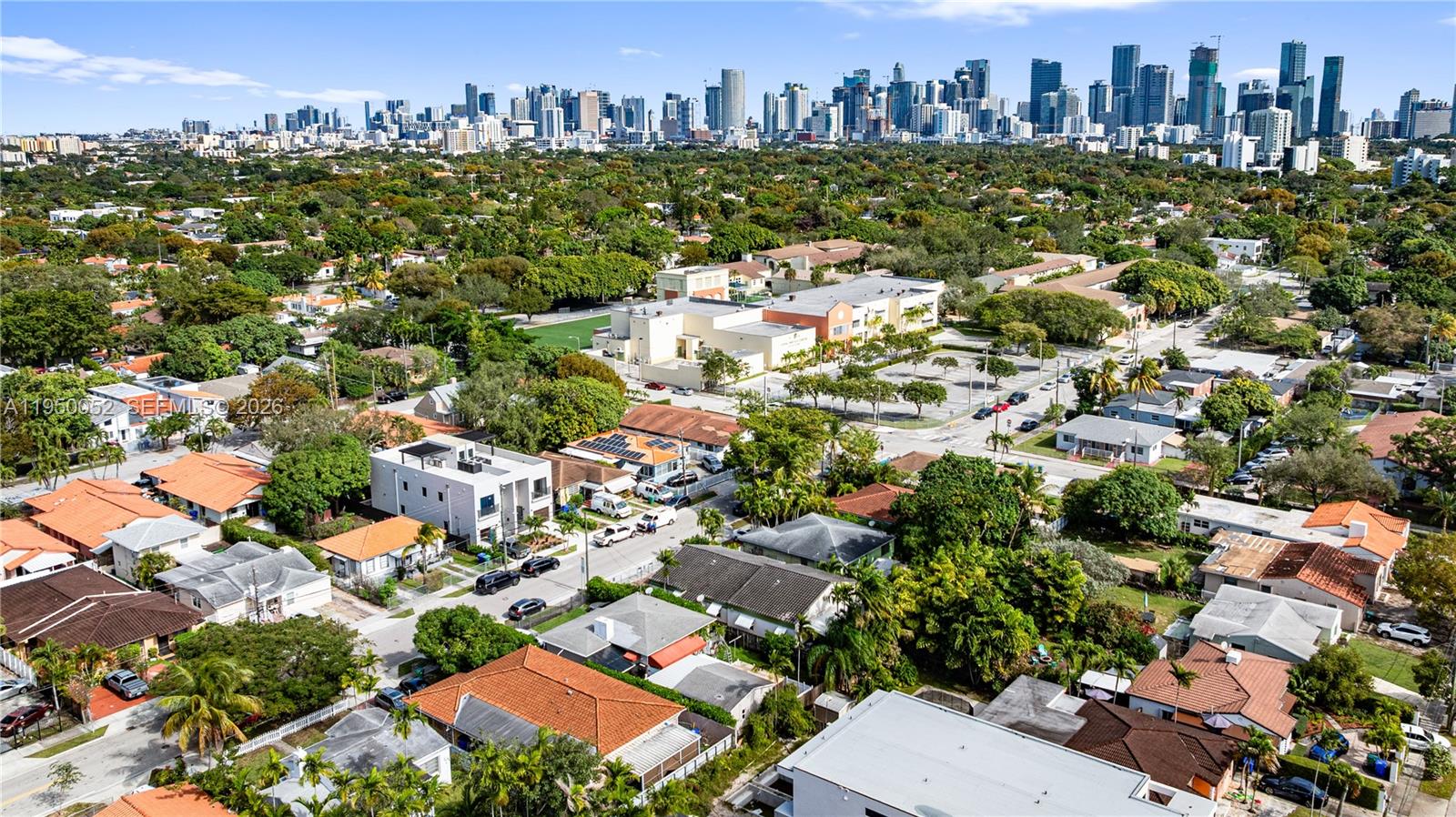 An aerial view shows a residential neighborhood with houses, trees, and a distant city skyline — 1428 SW 20th St, Miami FL 33145, MIAMI, FL