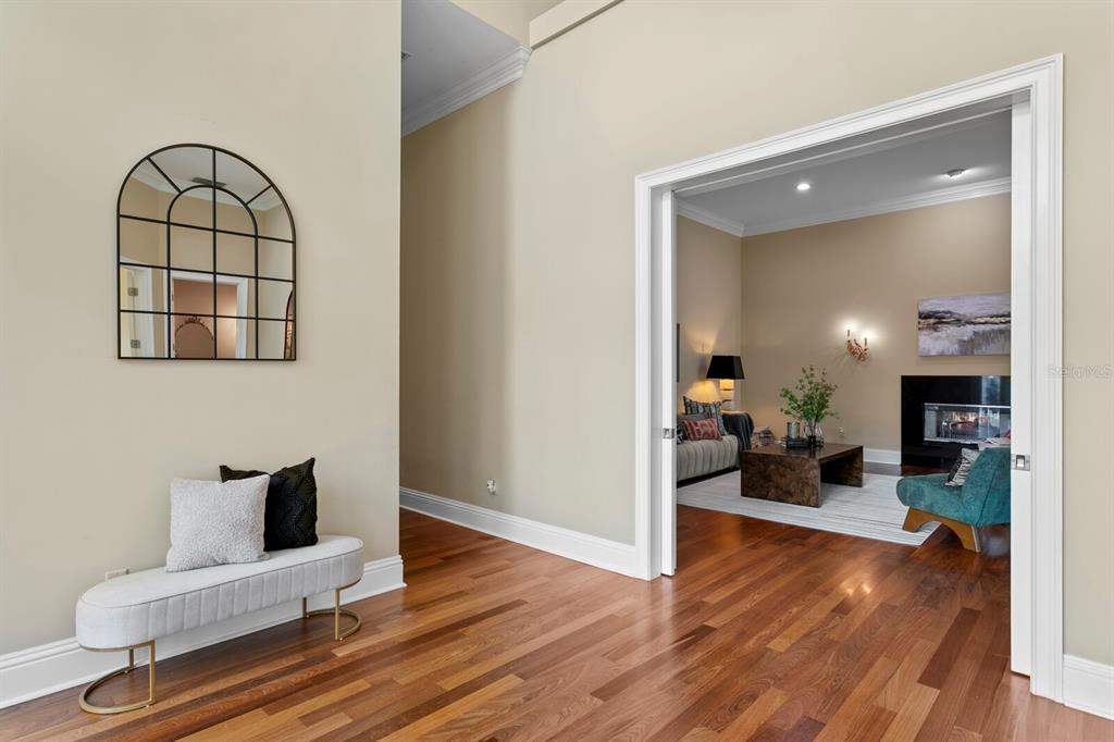 A hallway with a bench and arched mirror leads into a living room with hardwood floors — 16504 AVILA BOULEVARD, TAMPA, FL