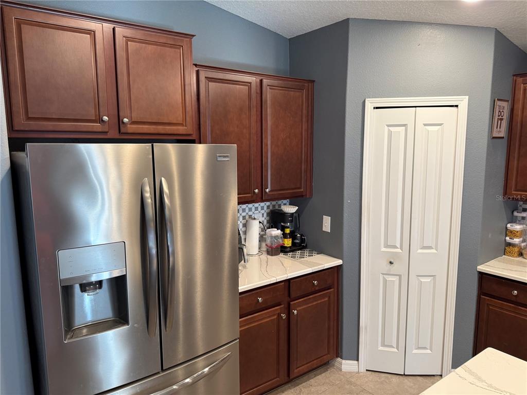 A kitchen features dark wood cabinets, stainless steel appliances, and white countertops with gray veining — 6629 WAGON TRAIL STREET, ZEPHYRHILLS, FL
