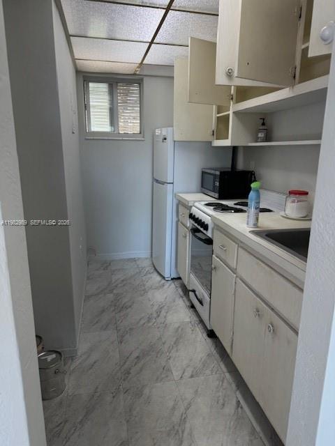 A narrow galley kitchen features white cabinets, a refrigerator, a stove, and marble-patterned tile flooring — 8601 SW 68th Ct # 23, Pinecrest FL 33156, PINECREST, FL