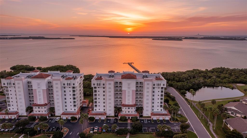 An aerial view of a multi-story residential building complex overlooking a bay at sunset — 2925 TERRA CEIA BAY BOULEVARD UNIT 2902, PALMETTO, FL