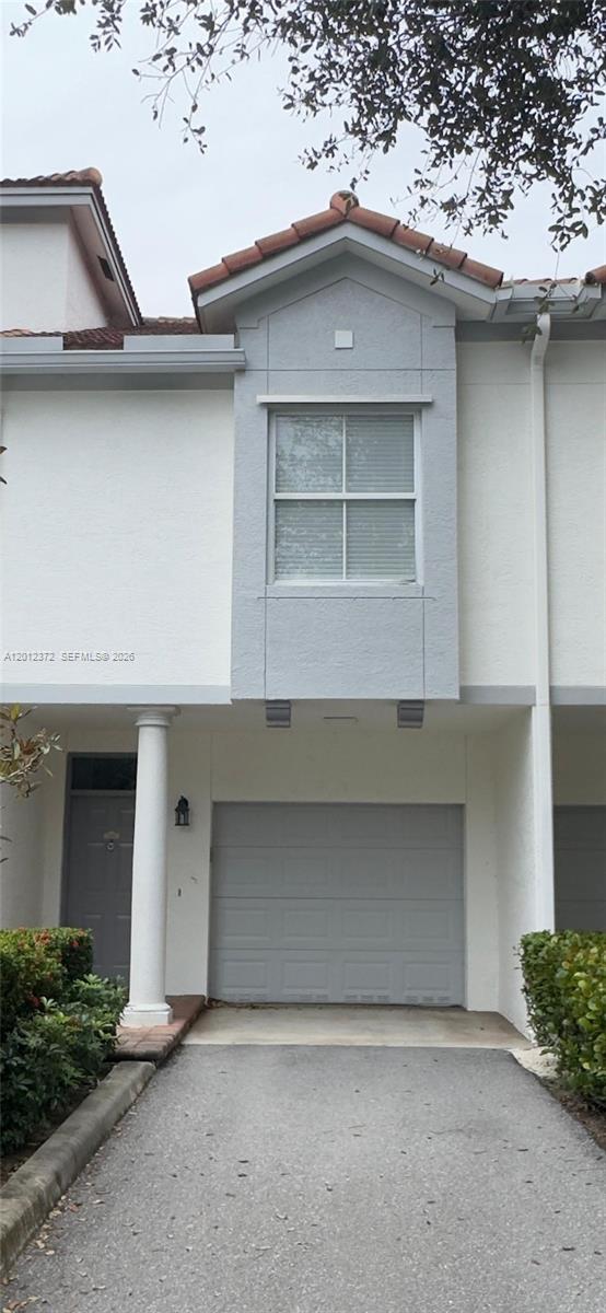 A two-story townhouse exterior features a gray garage door, a front door, and a window — 2042 Alta Meadows Ln # 1712, Delray Beach FL 33444, DELRAY BEACH, FL