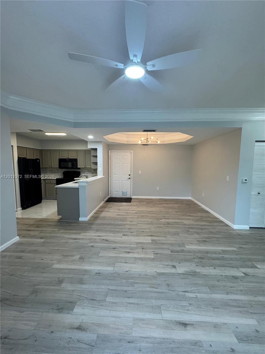 An open-concept living area features light wood-look flooring, a ceiling fan, and an adjacent kitchen — 2042 Alta Meadows Ln # 1712, Delray Beach FL 33444, DELRAY BEACH, FL