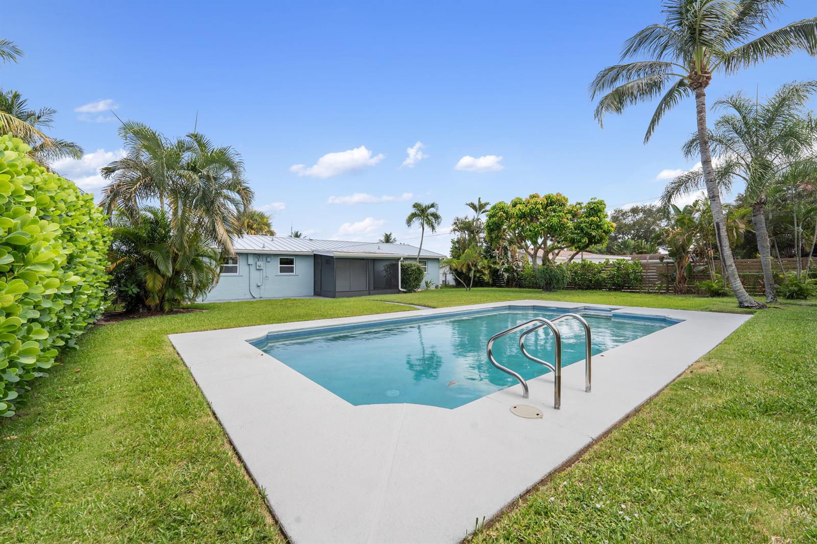 A backyard features a rectangular swimming pool with a metal ladder and a light-colored house — 204 Circle E, Jupiter FL 33458, JUPITER, FL