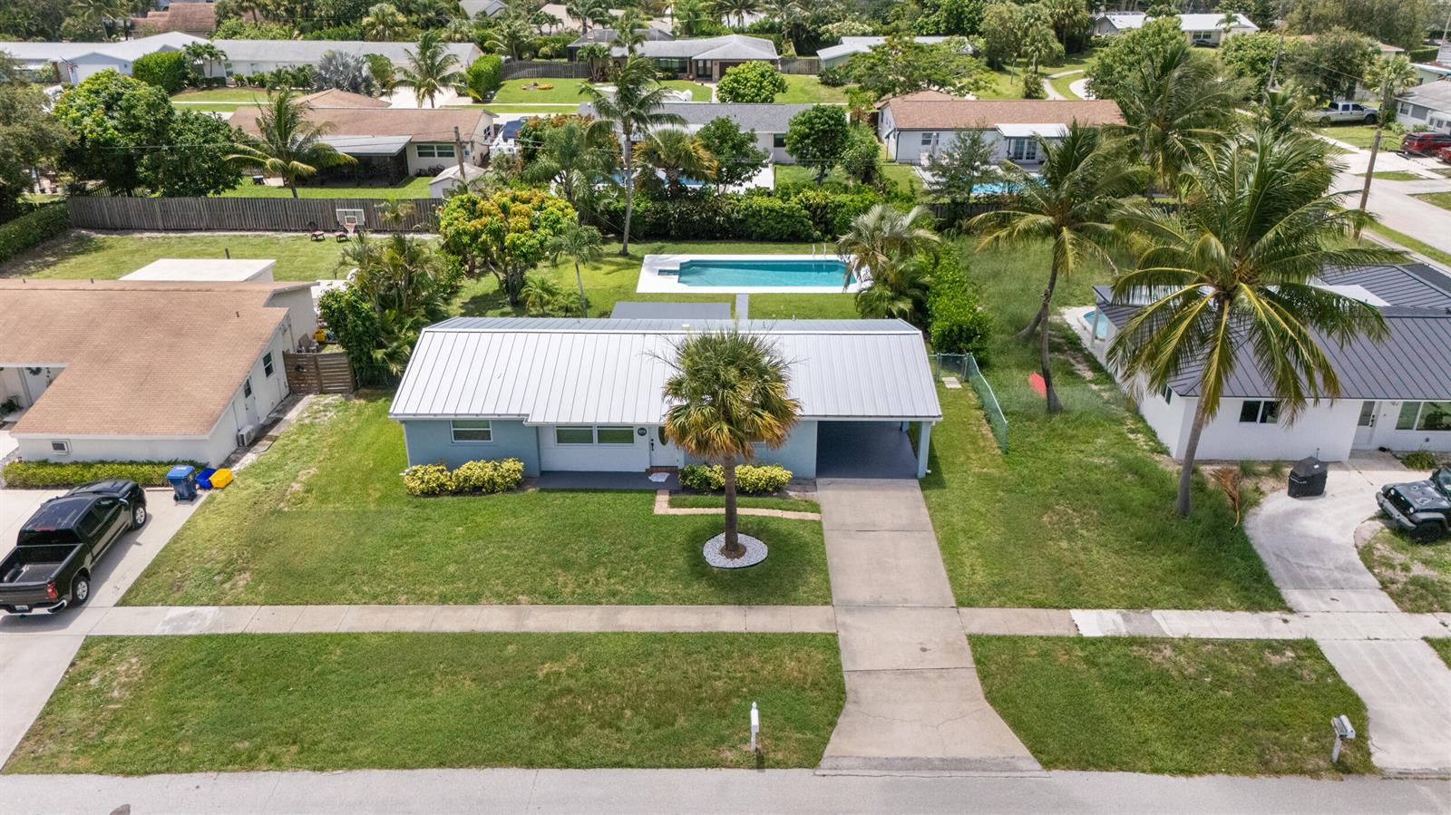 An aerial view of a single-story house with a metal roof, carport, and backyard pool — 204 Circle E, Jupiter FL 33458, JUPITER, FL