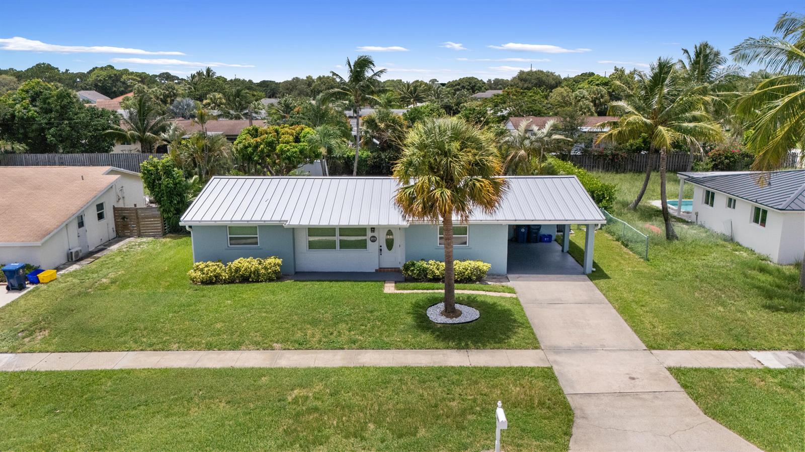 An aerial view shows a light blue single-story house with a metal roof and carport — 204 Circle E, Jupiter FL 33458, JUPITER, FL