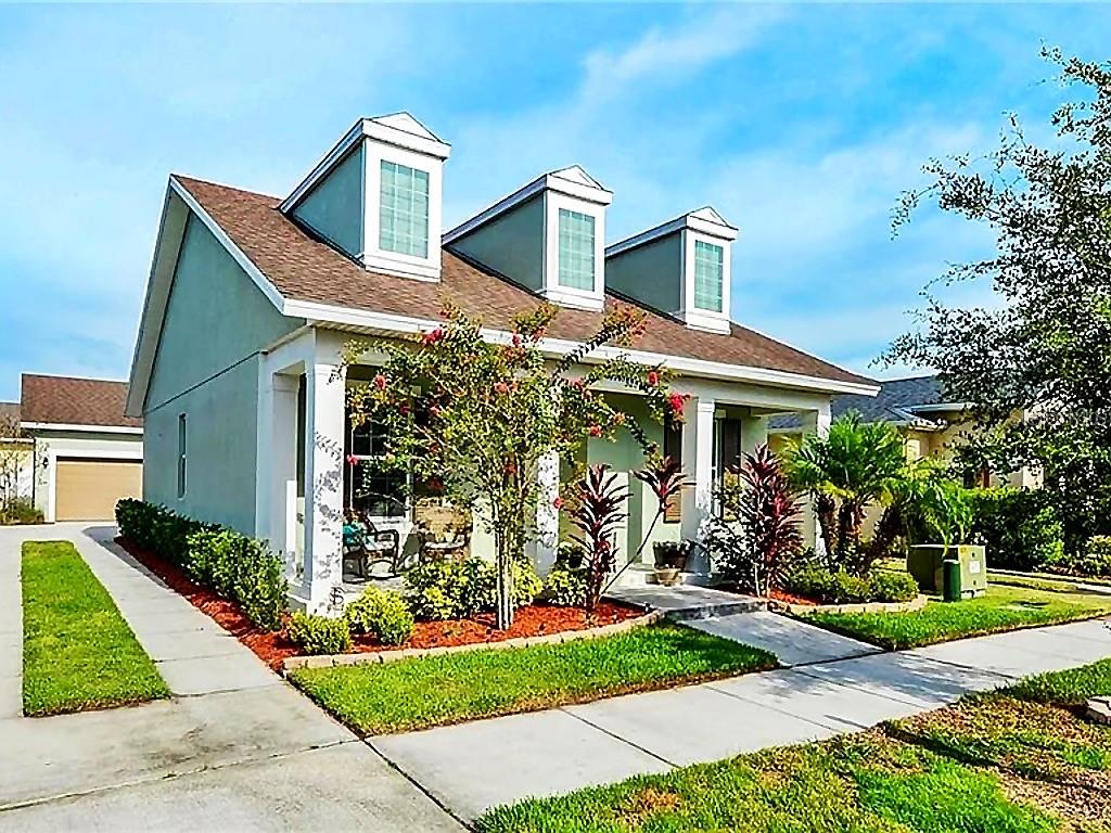 A light green house features a front porch, a white fence, and a paved driveway — 5253 SUNCATCHER DRIVE, WESLEY CHAPEL, FL