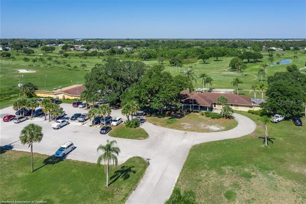 An aerial view shows a low-rise building with a parking lot surrounded by a golf course — 3603 PLACID LAKES BOULEVARD, LAKE PLACID, FL