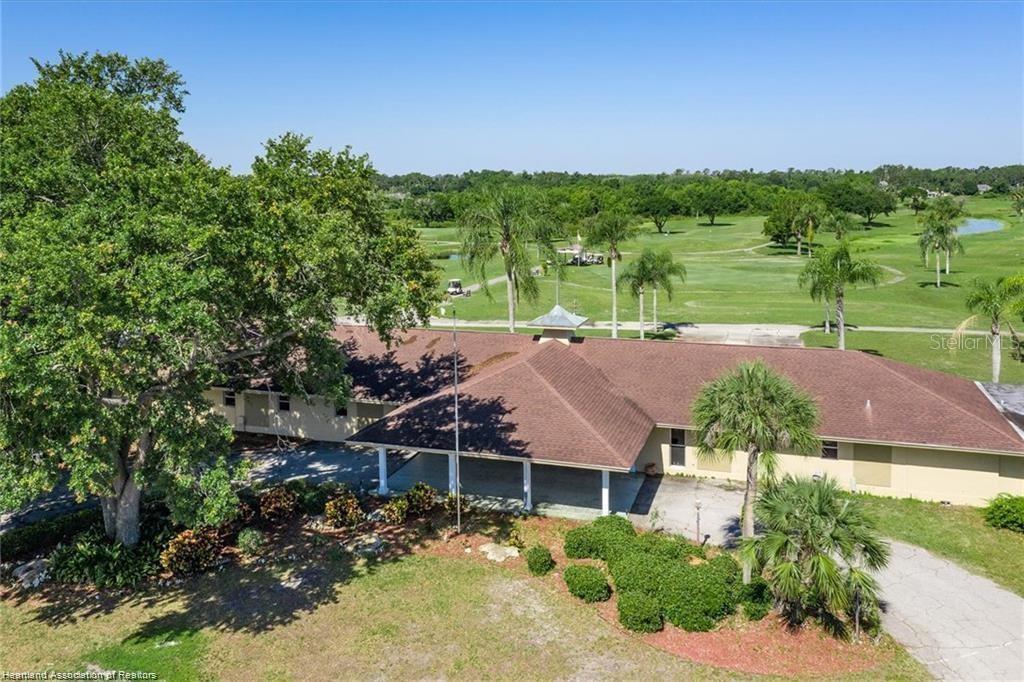An aerial view shows a single-story building with a brown roof overlooking a golf course — 3603 PLACID LAKES BOULEVARD, LAKE PLACID, FL