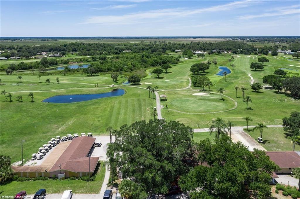 An aerial view shows a golf course with ponds, trees, and a clubhouse building — 3603 PLACID LAKES BOULEVARD, LAKE PLACID, FL