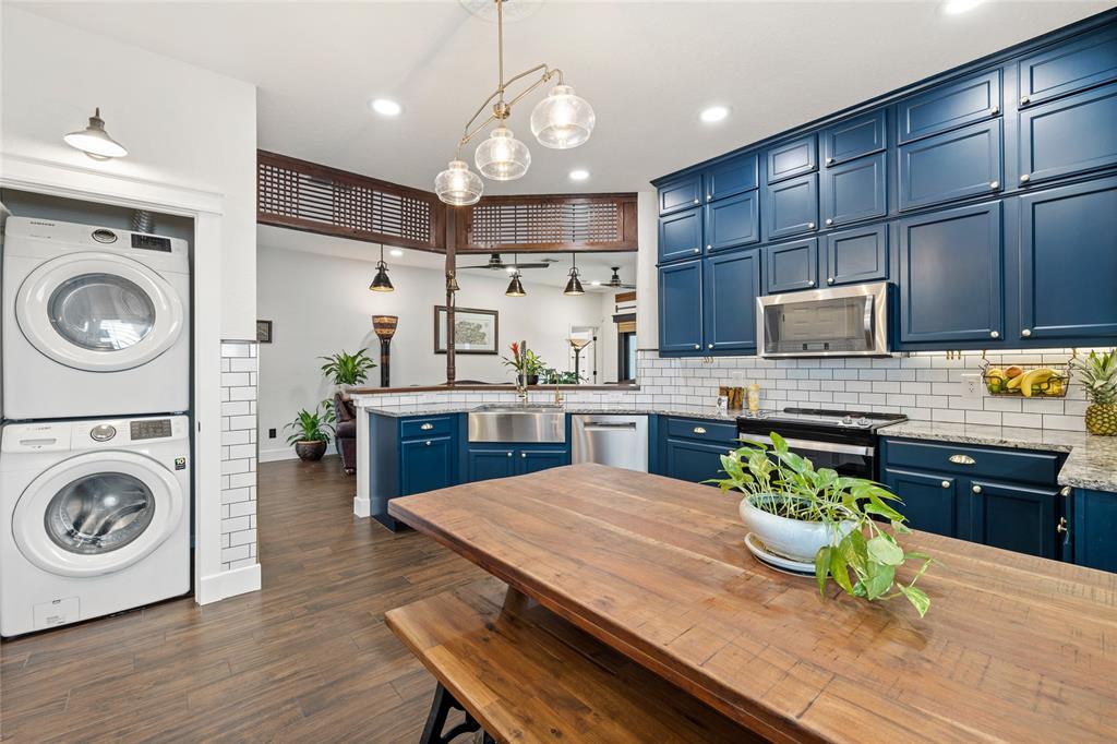 A kitchen features blue cabinets, a wooden island, and a stacked washer and dryer unit — 16644 CARIBBEAN BREEZE WAY, CLERMONT, FL