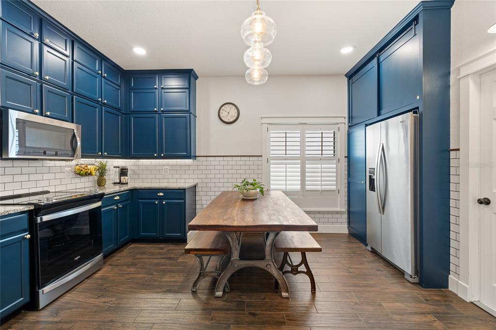 A kitchen features blue cabinets, a wooden dining table, and stainless steel appliances — 16644 CARIBBEAN BREEZE WAY, CLERMONT, FL