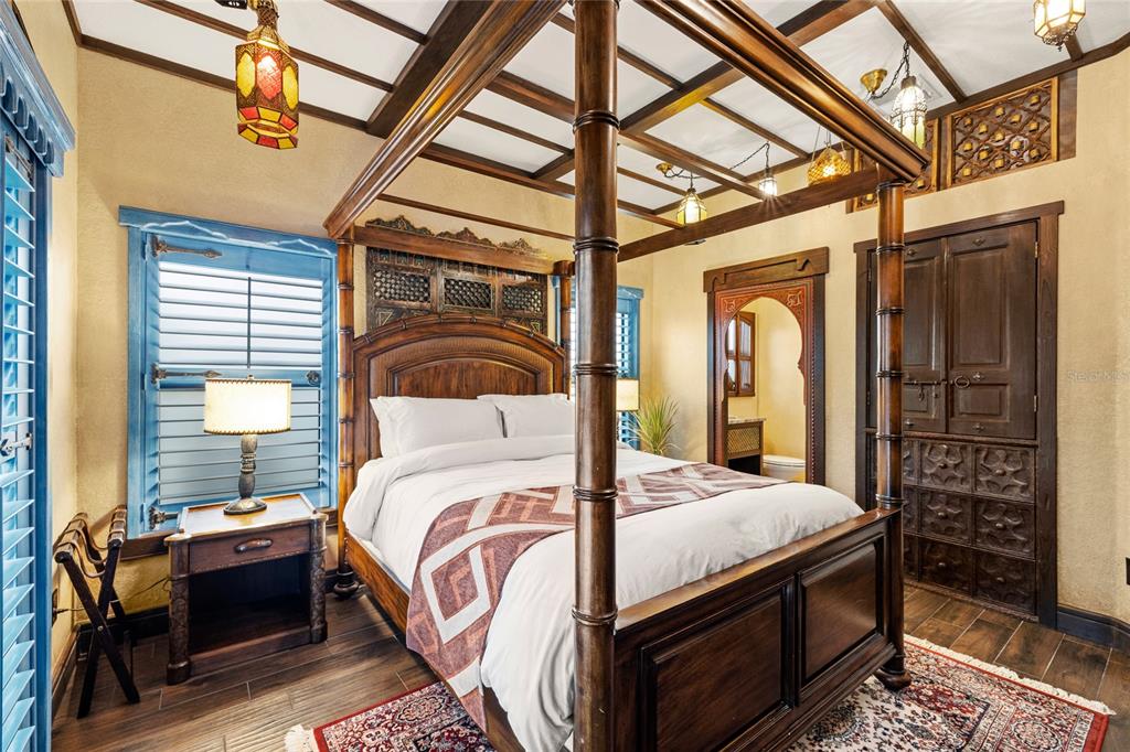 A bedroom features a four-poster wooden bed, ornate carved wood accents, and blue window shutters — 16644 CARIBBEAN BREEZE WAY, CLERMONT, FL