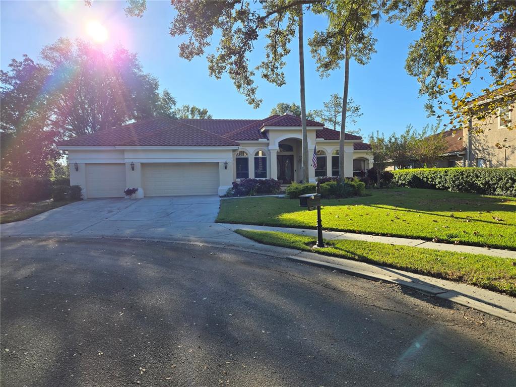 A single-story house with a red tile roof, three-car garage, and a manicured front lawn — 9127 WOODRIDGE RUN DRIVE, TAMPA, FL