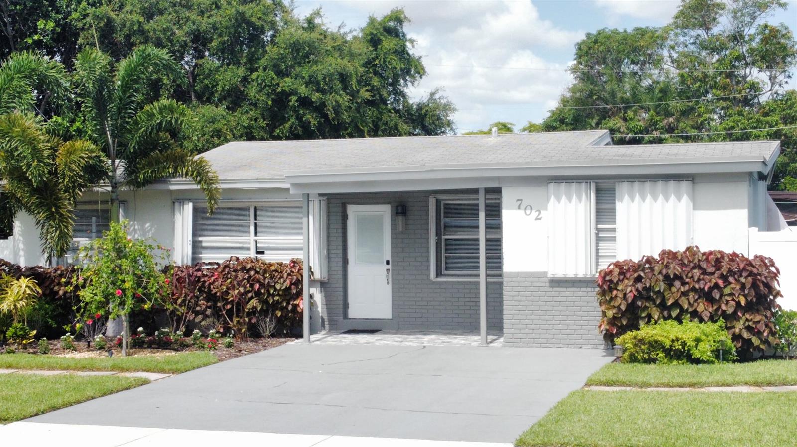 A single-story house with a gray brick facade, a white door, and a concrete driveway — 702 SW 1st Street, Delray Beach FL 33444, DELRAY BEACH, FL