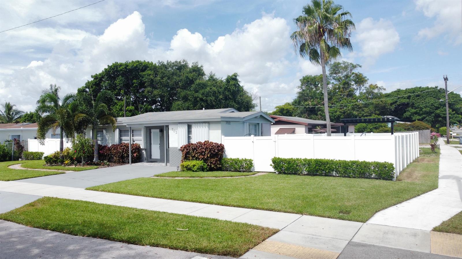 A single-story house with a white fence, a palm tree, and a manicured lawn — 702 SW 1st Street, Delray Beach FL 33444, DELRAY BEACH, FL