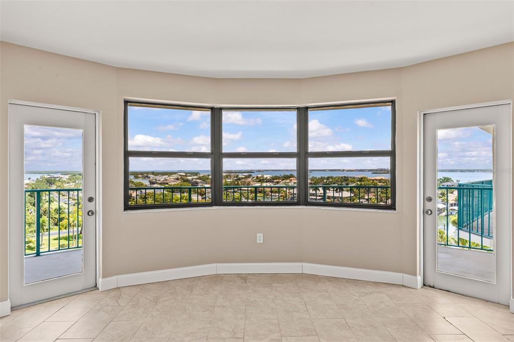 An empty room with tile flooring, three large windows, and two glass doors to balconies — 670 ISLAND WAY UNIT 800, CLEARWATER BEACH, FL