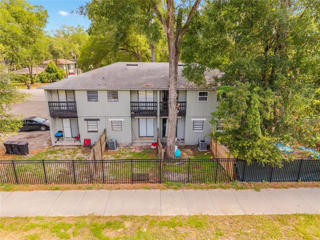 An exterior view of a two-story apartment building with balconies and a fenced backyard — 723 SW 69TH STREET, GAINESVILLE, FL