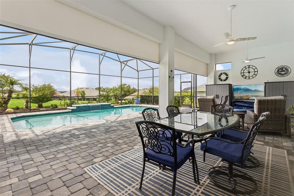 A covered patio features a dining set, ceiling fans, and a swimming pool with a fountain — 5141 GREENS DRIVE, LADY LAKE, FL