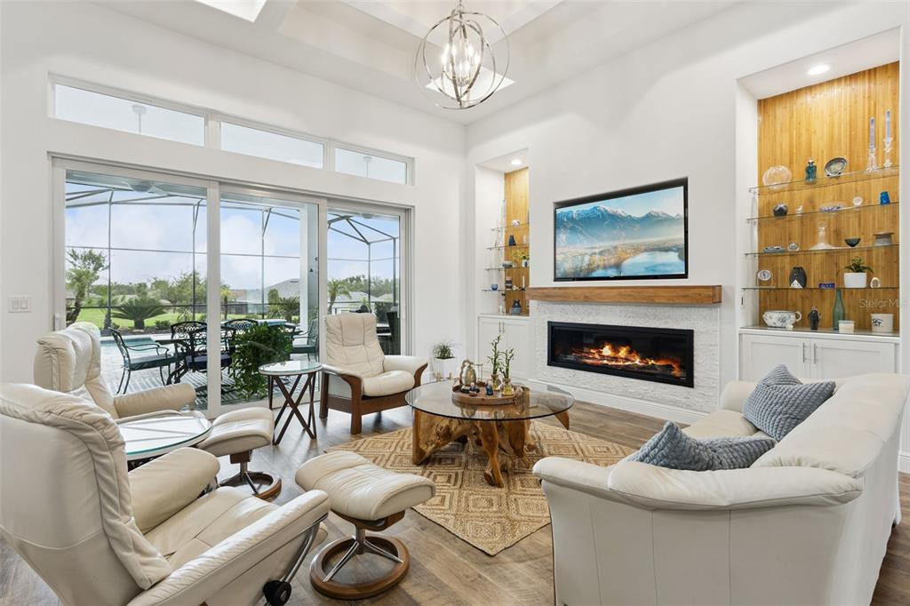 A living room features a fireplace, built-in shelving, white leather furniture, and large sliding doors — 5141 GREENS DRIVE, LADY LAKE, FL