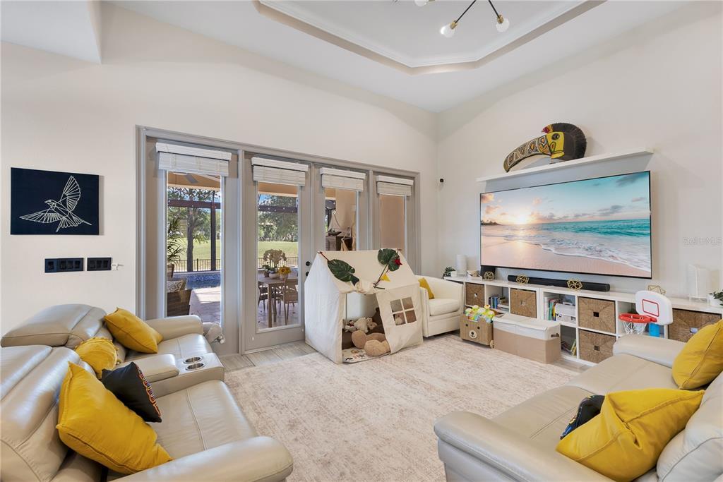 A living room features light leather sofas, a large television, and a children's play tent — 10720 GAWSWORTH POINT, ORLANDO, FL