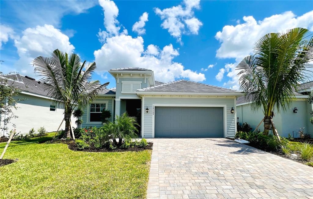 A light blue single-story house features a two-car garage, paver driveway, and two palm trees — 14700 CHERRY BLOSSOM WAY, PUNTA GORDA, FL