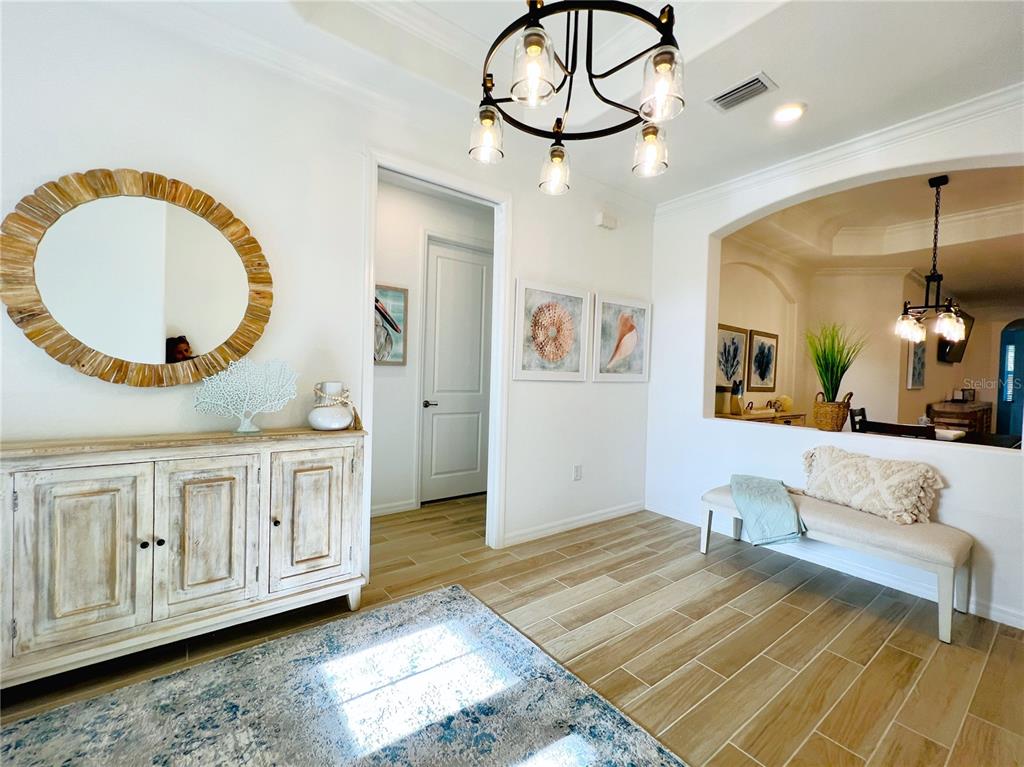 A bright entryway features a wooden console table, a round mirror, and a bench — 14700 CHERRY BLOSSOM WAY, PUNTA GORDA, FL