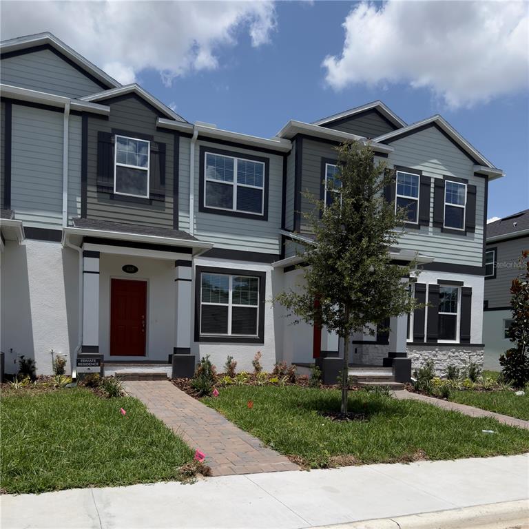 A two-story townhouse exterior features light blue siding, white stucco, and a red front door — 438 LADY PALM STREET, APOPKA, FL