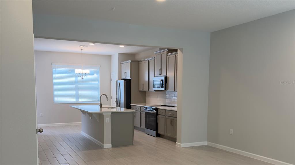 A kitchen with gray cabinets, a central island, and light-colored tile flooring — 438 LADY PALM STREET, APOPKA, FL