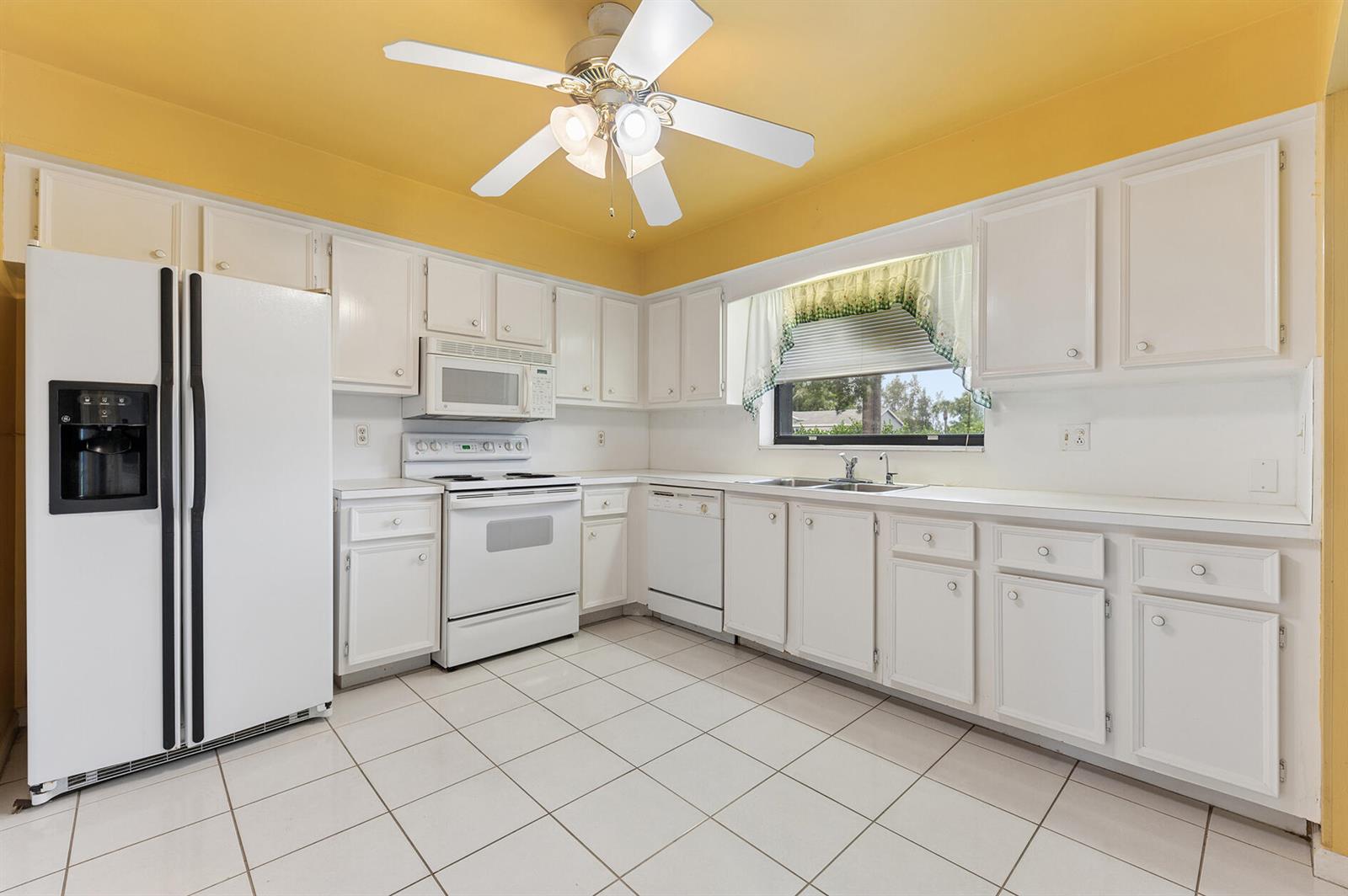 A kitchen with white cabinets, white appliances, tiled floors, and yellow walls — 9795 Tabebuia Tree Drive # B, Boynton Beach FL 33436, BOYNTON BEACH, FL