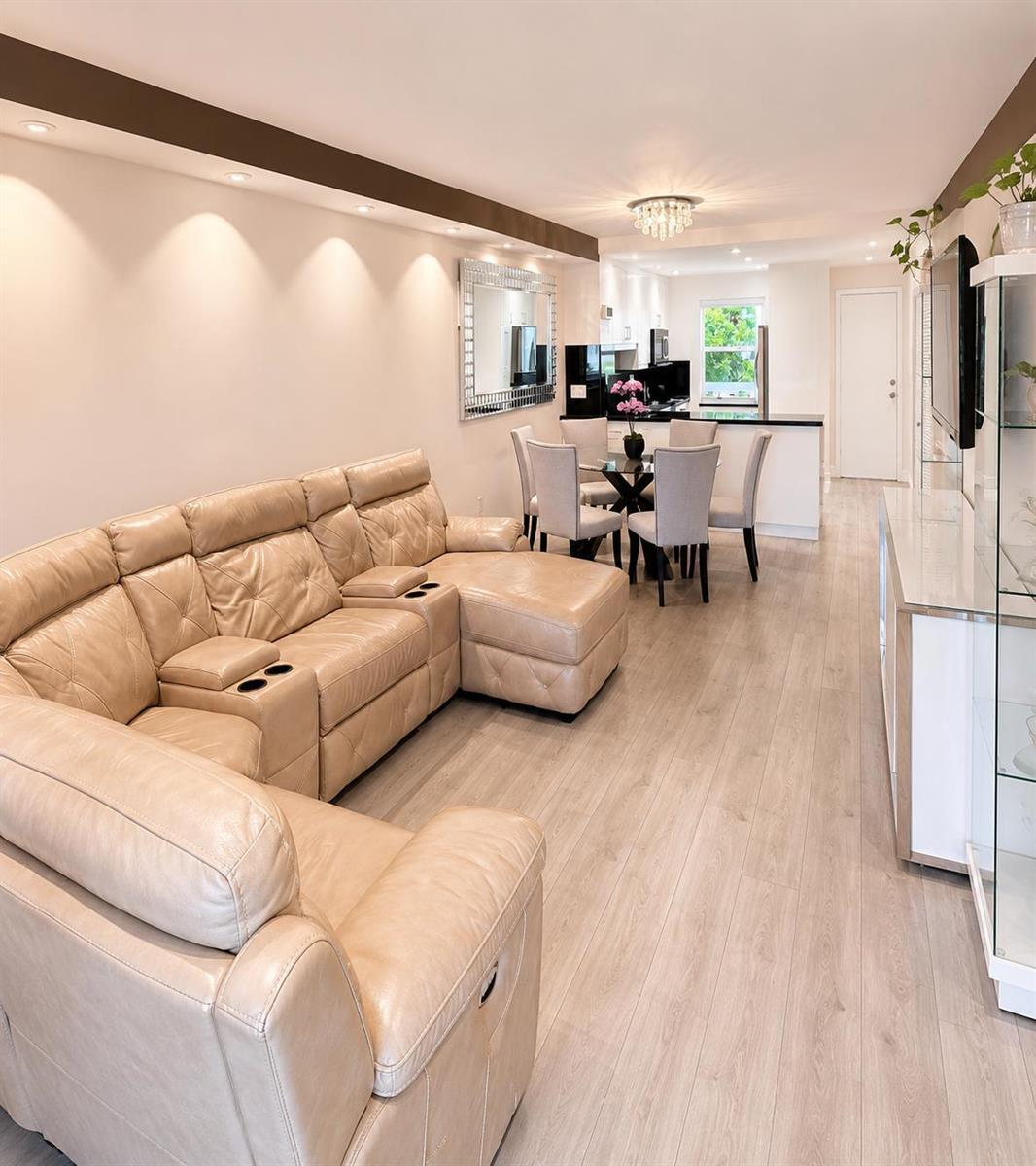 A living room with a beige sectional sofa, dining area, and light wood-look flooring — 9880 Marina Boulevard # 1520, Boca Raton FL 33428, BOCA RATON, FL