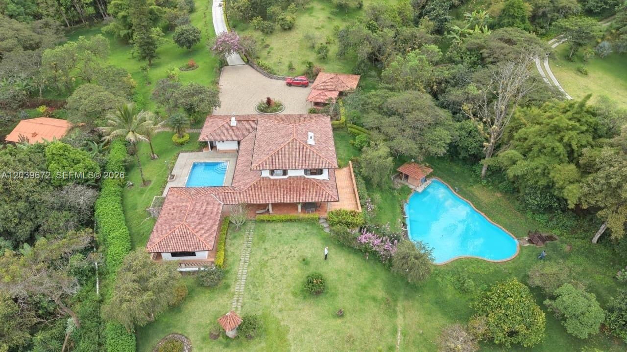 An aerial view shows a house with a red tile roof, two pools, and gardens — NA Via Guadaleg (Ecuador) NA Via Guadaleg (Ecuador), FL