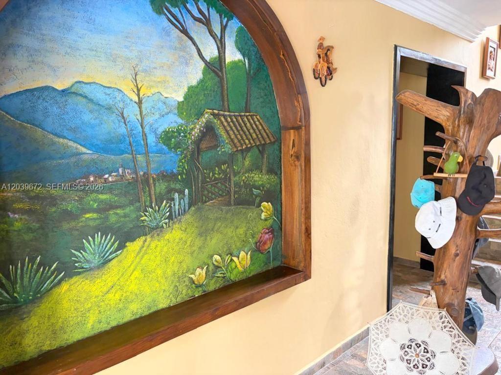 A wall features a large arched mural of a landscape next to a wooden coat rack — NA Via Guadaleg (Ecuador) NA Via Guadaleg (Ecuador), FL