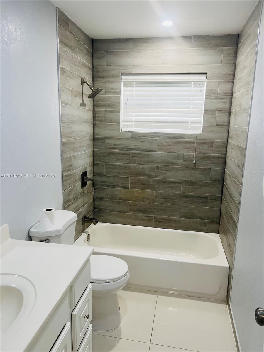 A bathroom features a white vanity, a toilet, and a bathtub with wood-look tile walls — 8401 NW 20th Ct, Sunrise FL 33322, SUNRISE, FL