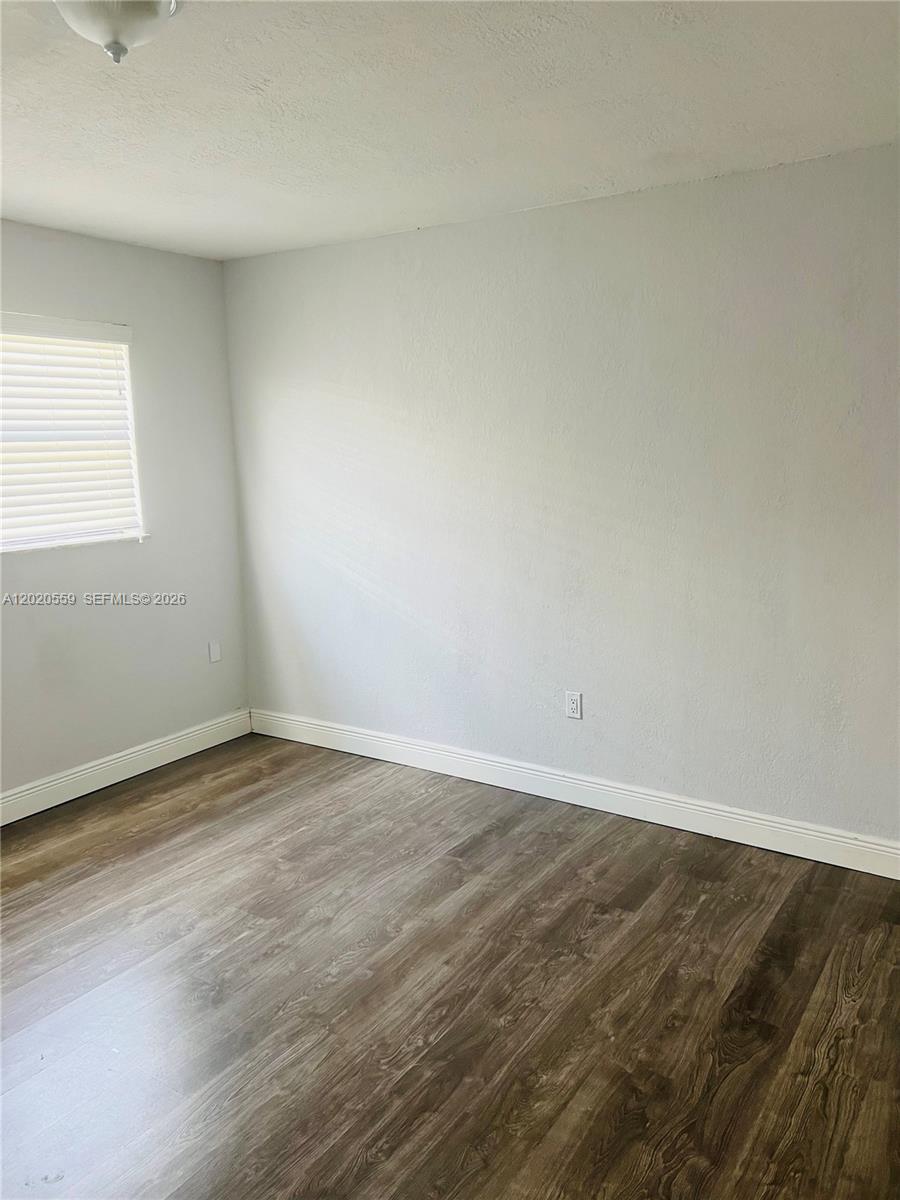 An empty room features light gray walls, white trim, and dark wood-look flooring — 8401 NW 20th Ct, Sunrise FL 33322, SUNRISE, FL
