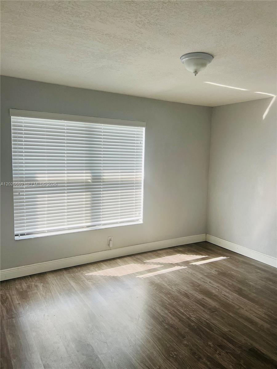 An empty room features light gray walls, wood-look flooring, and a window with white blinds — 8401 NW 20th Ct, Sunrise FL 33322, SUNRISE, FL