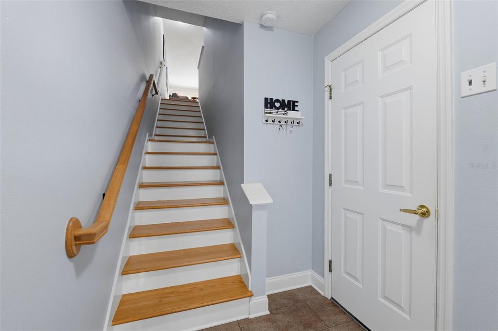 A staircase with wooden treads and white risers leads upward from a tiled entryway — 381 MADEIRA CIRCLE, TIERRA VERDE, FL