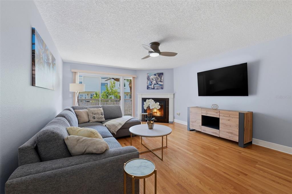 A living room features a gray sectional sofa, a fireplace, and a wall-mounted television — 381 MADEIRA CIRCLE, TIERRA VERDE, FL