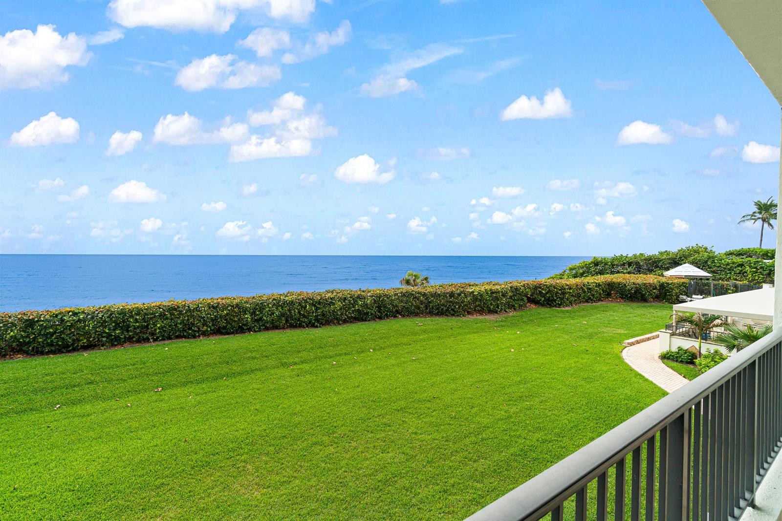 A view from a balcony overlooking a green lawn, a hedge, and the ocean — 800 Ocean Drive # 204, Juno Beach FL 33408, JUNO BEACH, FL