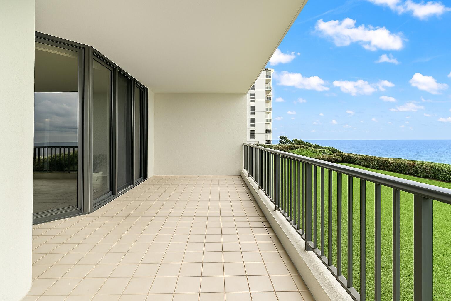 A spacious balcony with beige tile flooring, a metal railing, and views of the ocean — 800 Ocean Drive # 204, Juno Beach FL 33408, JUNO BEACH, FL