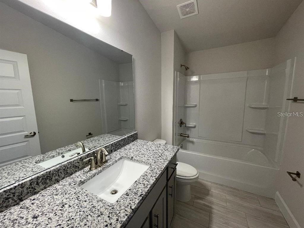 A bathroom features a granite vanity, a white sink, and a shower-tub combination — 9351 HIGHLAND HILLS DR STREET, HUDSON, FL