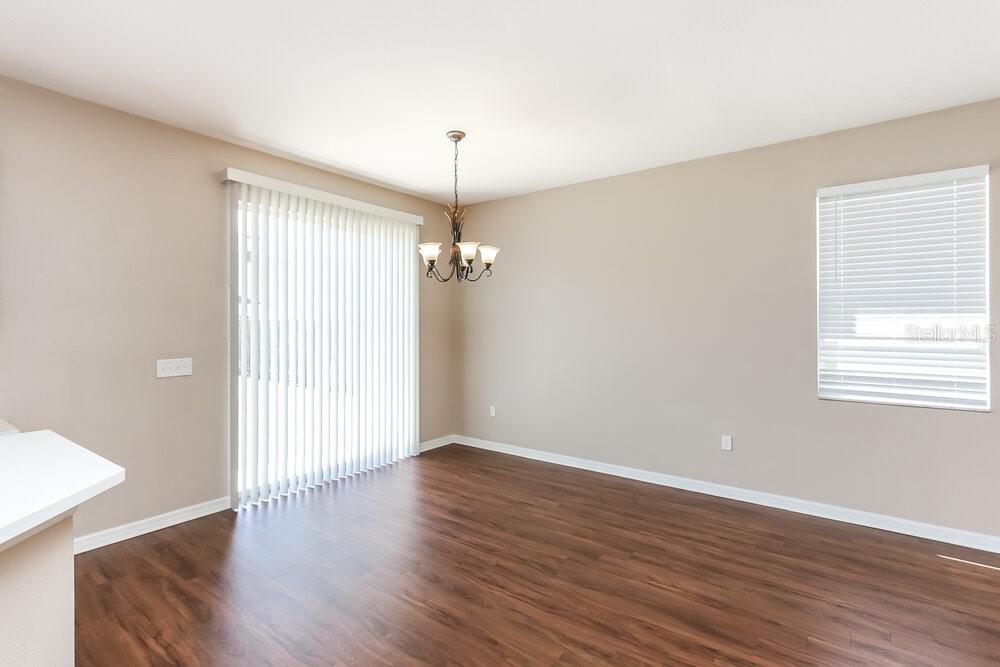 A dining room with wood-look flooring, a chandelier, vertical blinds, and a window — 12122 FERN HAVEN AVENUE, GIBSONTON, FL