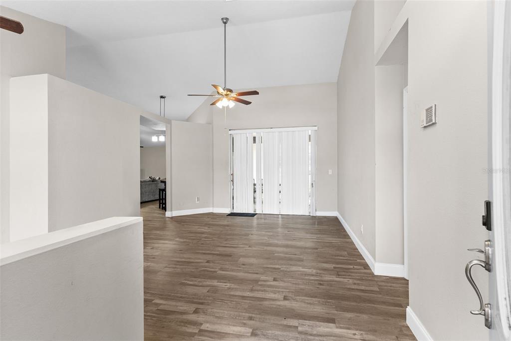An empty living room features vaulted ceilings, a ceiling fan, and wood-look flooring — 12106 SHADY FOREST DRIVE, RIVERVIEW, FL