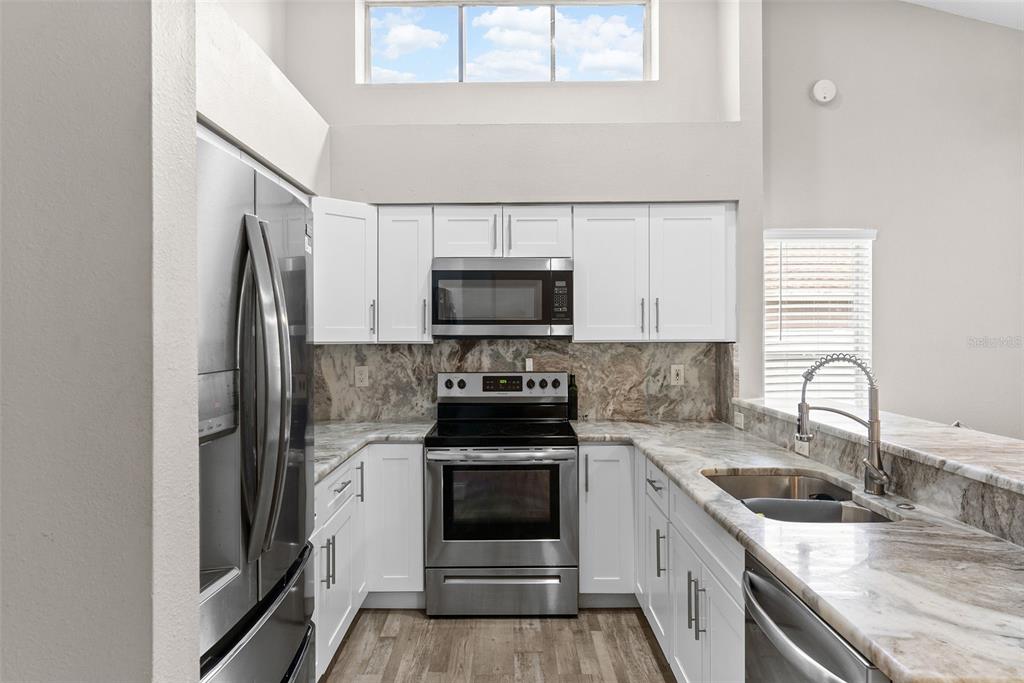 A kitchen features white cabinets, stainless steel appliances, and marble-patterned countertops — 12106 SHADY FOREST DRIVE, RIVERVIEW, FL