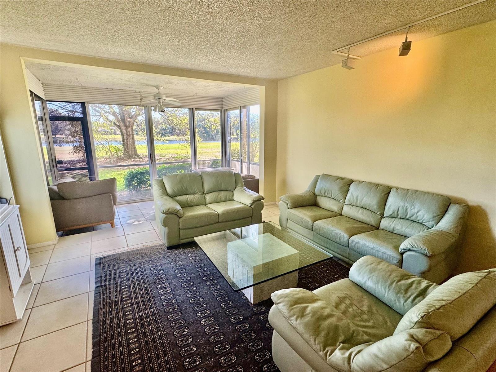 A living room features light green leather furniture, a glass coffee table, and large windows — 804 Cypress Boulevard # 106, Pompano Beach FL 33069, POMPANO BEACH, FL