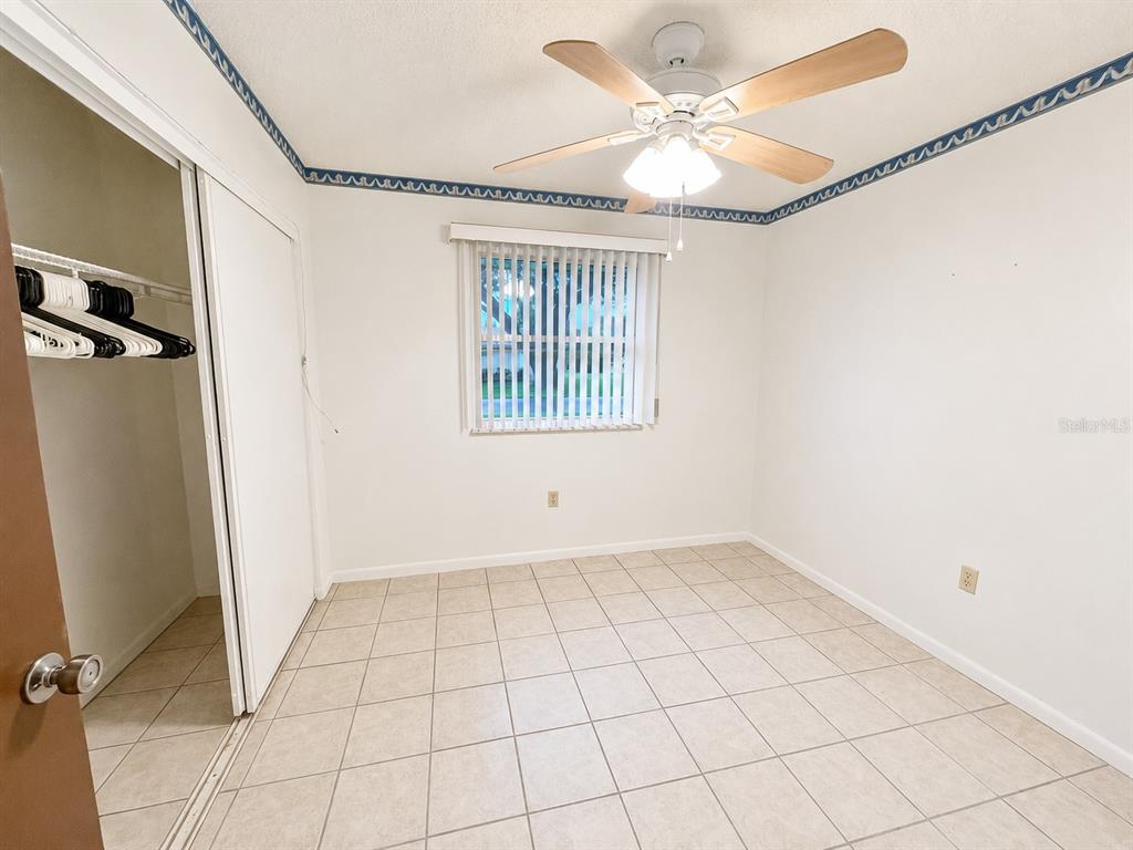 An empty bedroom features white walls, a tiled floor, a ceiling fan, and a closet — 8565 SW 109TH STREET, OCALA, FL