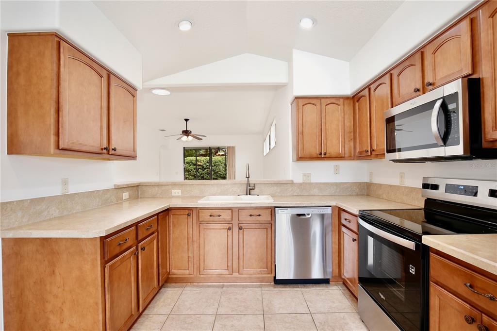 A kitchen with wood cabinets, stainless steel appliances, and tile flooring — 27210 STONEY BROOK DRIVE, LEESBURG, FL