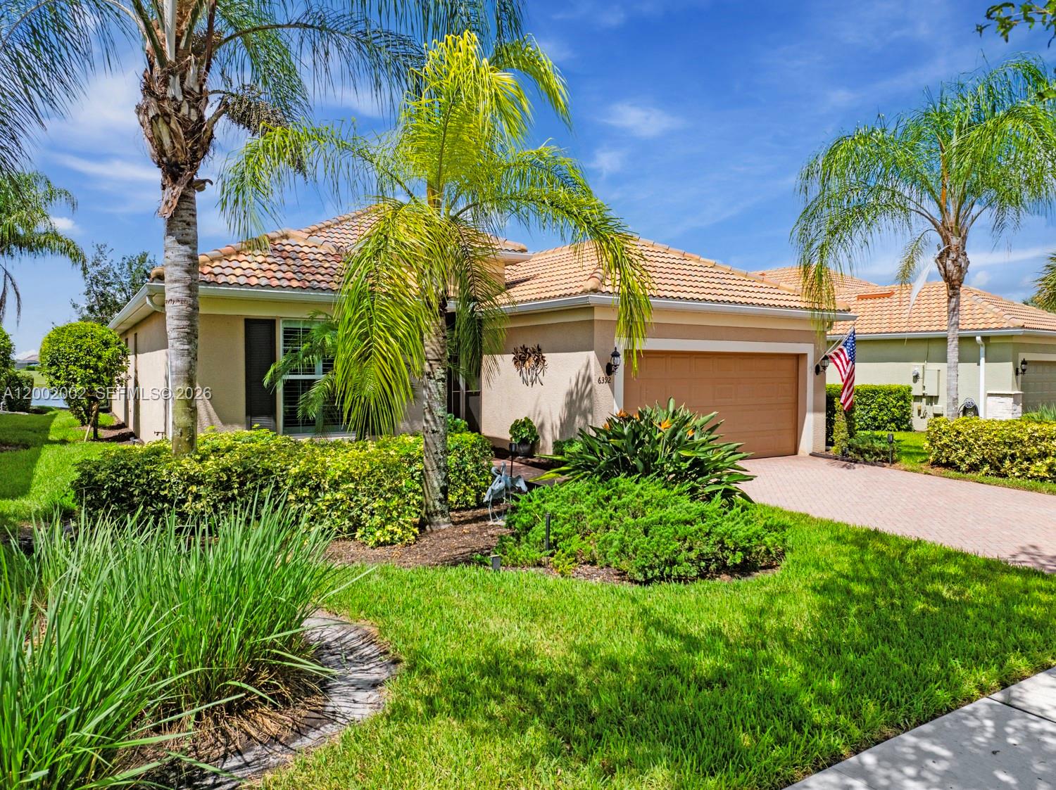 A single-story house with a tan stucco exterior, tile roof, and a paved driveway — 6392 Liberty St, Ave Maria FL 34142, AVE MARIA, FL