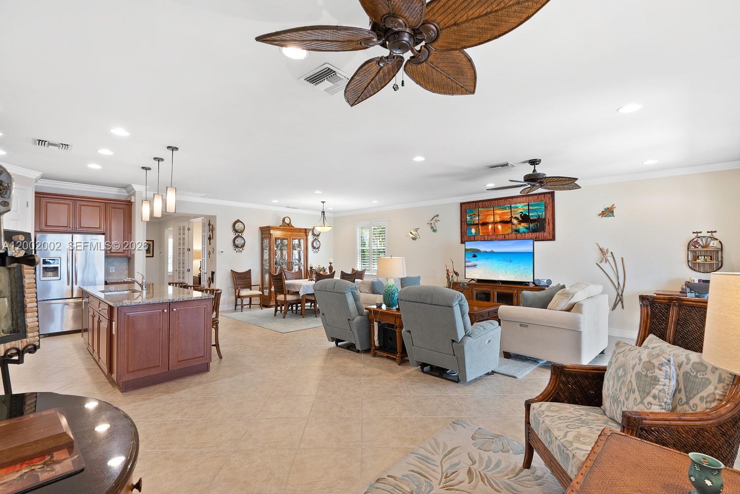 An open-concept living area features a kitchen with wood cabinets, a dining space, and furniture — 6392 Liberty St, Ave Maria FL 34142, AVE MARIA, FL